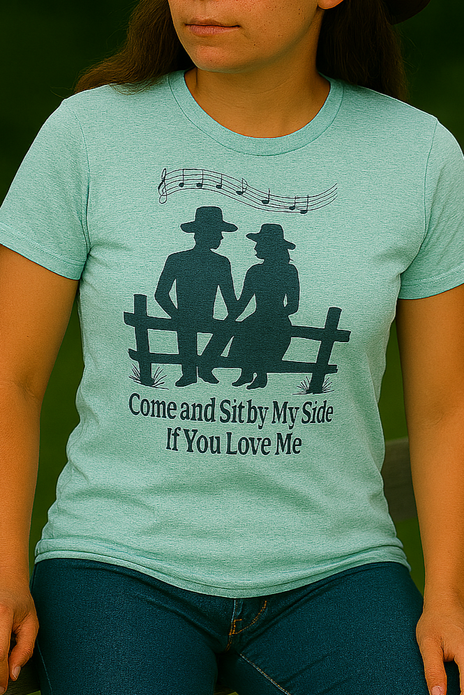 Cowgirl in mint green tee seated on a rustic fence, surrounded by vibrant greenery and soft shadows.