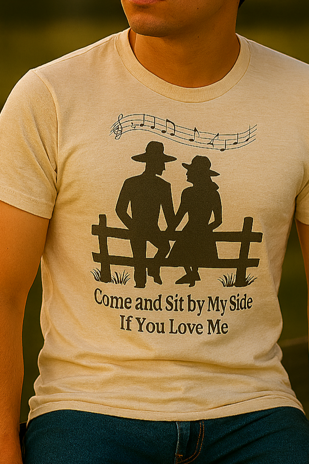 Cowboy in soft cream T-shirt seated on a fence, gazing into the distance with a longing expression as sunset light glows behind him.