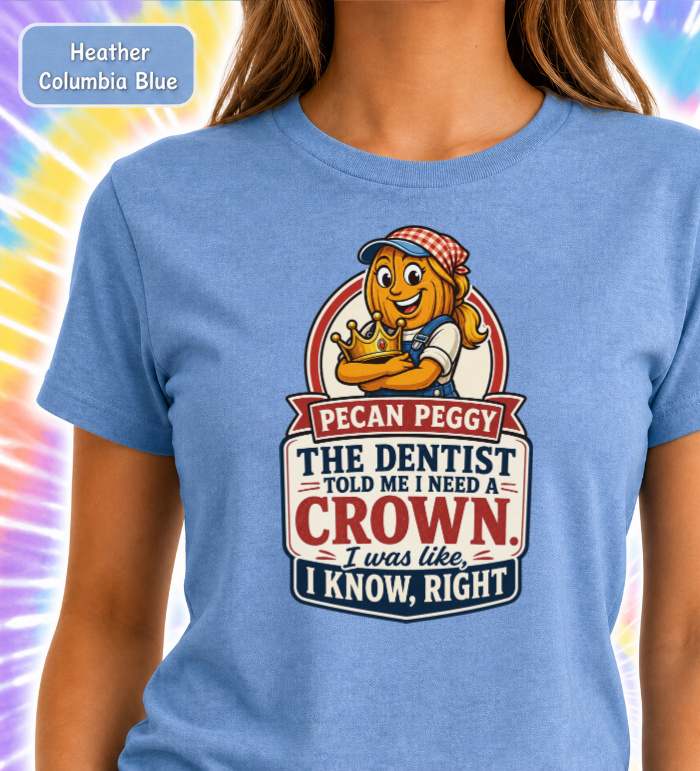 A woman wearing a heather blue graphic T-shirt with a cartoon pecan character and the text 'Pecan Peggy The Dentist Told Me I Need a Crown. I was like, I Know, Right'.
