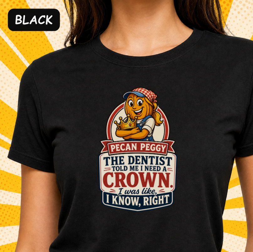 A black short-sleeve graphic T-shirt worn by a model, featuring a cartoon pecan character and the text 'PECAN PEGGY THE DENTIST TOLD ME I NEED A CROWN. I was like, I KNOW, RIGHT'.