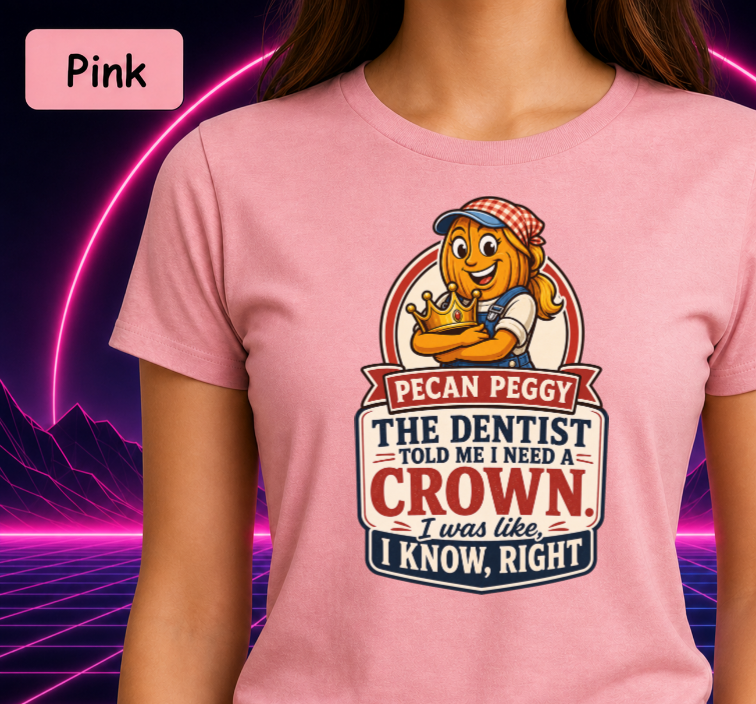 A pink short-sleeve graphic T-shirt worn by a model, featuring a cartoon pecan character and the text 'Pecan Peggy THE DENTIST TOLD ME I NEED A CROWN I was like, I KNOW, RIGHT'. A pink label in the top-left corner reads 'Pink'.
