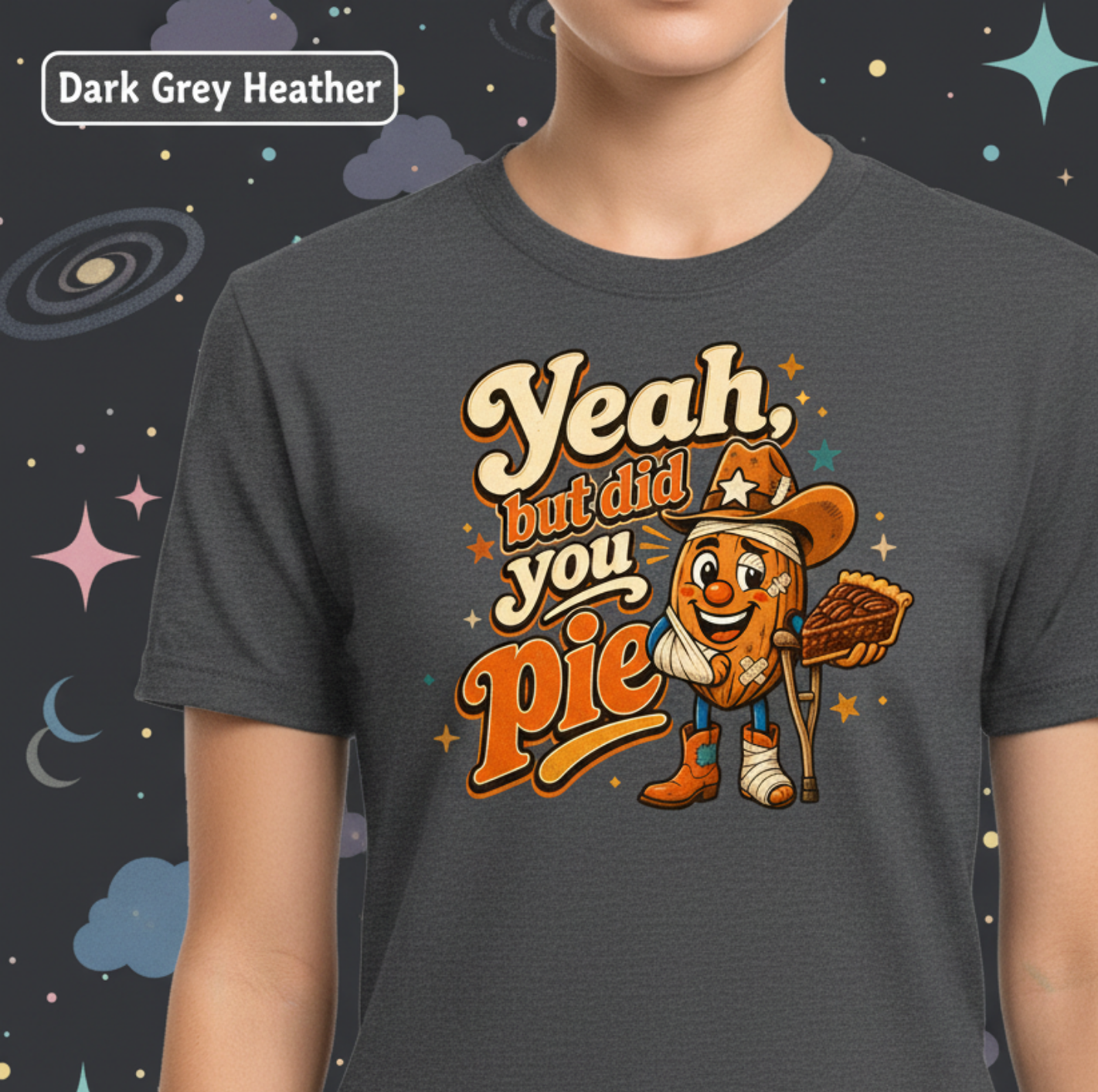 A dark grey heather t-shirt featuring a cartoon graphic of a cowboy character holding a pie and wearing a star hat, with the text 'Yeah, but did you Pie'. The image shows a person wearing the shirt, cropped from the neck down, against a dark grey space-themed background with stars and planets.