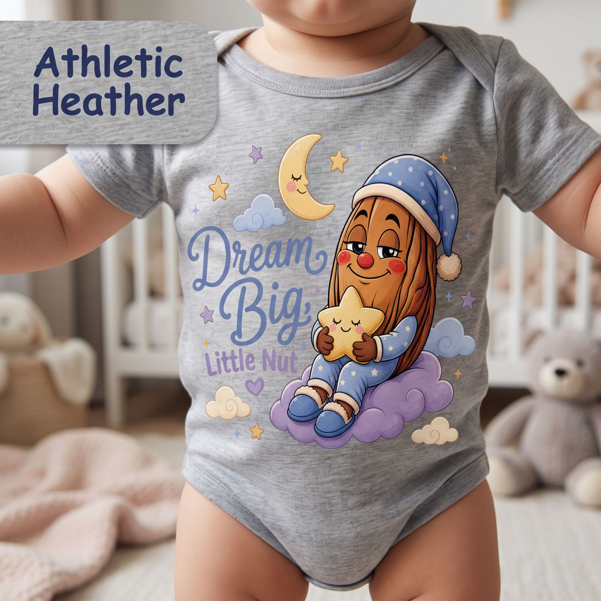 A baby wearing a heather gray short-sleeve bodysuit with a colorful cartoon graphic of a child holding a star on a cloud, with the text 'Dream Big, Little Nut.' A gray label in the top left reads 'Athletic Heather.