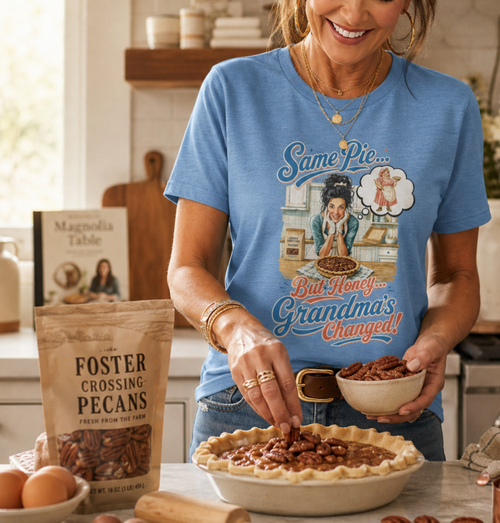 Bella+Canvas t-shirt displaying a graphic of a modern, stylish grandma in a kitchen reflecting on traditional grandmas, with retro typography reading "Same Pie, Grandma's Changed". Using Foster Crossing Pecans.