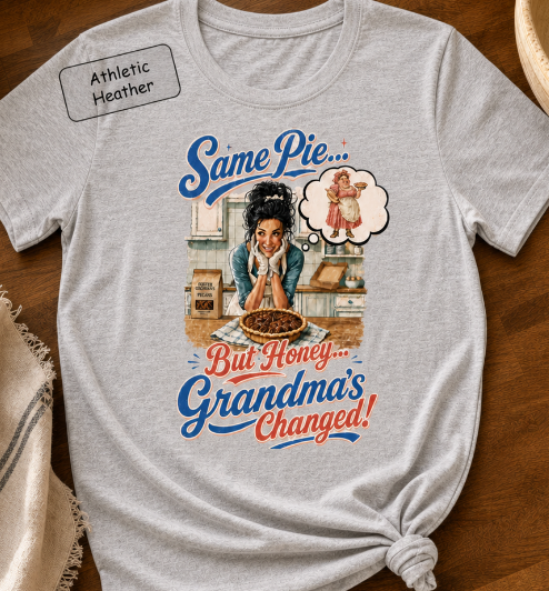 Bella+Canvas t-shirt displaying a graphic of a modern, stylish grandma in a kitchen reflecting on traditional grandmas, with retro typography reading "Same Pie, Grandma's Changed".