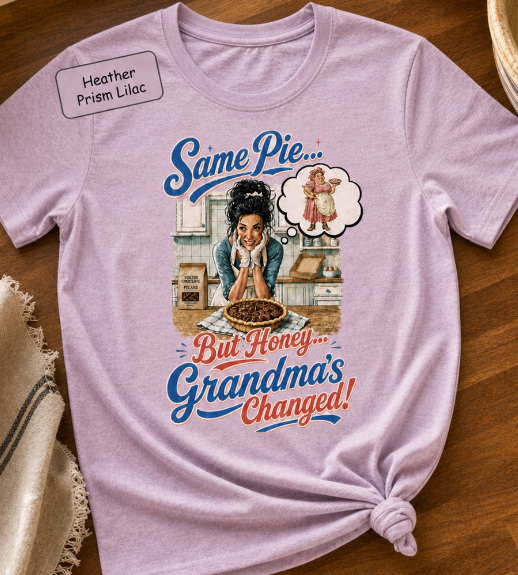 Bella+Canvas t-shirt displaying a graphic of a modern, stylish grandma in a kitchen reflecting on traditional grandmas, with retro typography reading "Same Pie, Grandma's Changed".