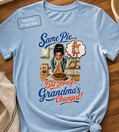 Bella+Canvas t-shirt displaying a graphic of a modern, stylish grandma in a kitchen reflecting on traditional grandmas, with retro typography reading "Same Pie, Grandma's Changed".