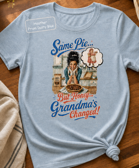 Bella+Canvas t-shirt displaying a graphic of a modern, stylish grandma in a kitchen reflecting on traditional grandmas, with retro typography reading "Same Pie, Grandma's Changed".
