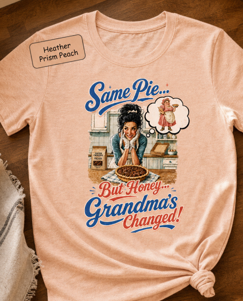 Bella+Canvas t-shirt displaying a graphic of a modern, stylish grandma in a kitchen reflecting on traditional grandmas, with retro typography reading "Same Pie, Grandma's Changed".