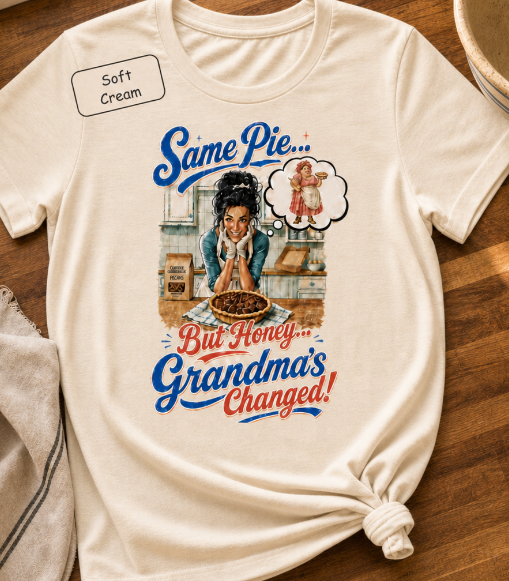 Bella+Canvas t-shirt displaying a graphic of a modern, stylish grandma in a kitchen reflecting on traditional grandmas, with retro typography reading "Same Pie, Grandma's Changed".