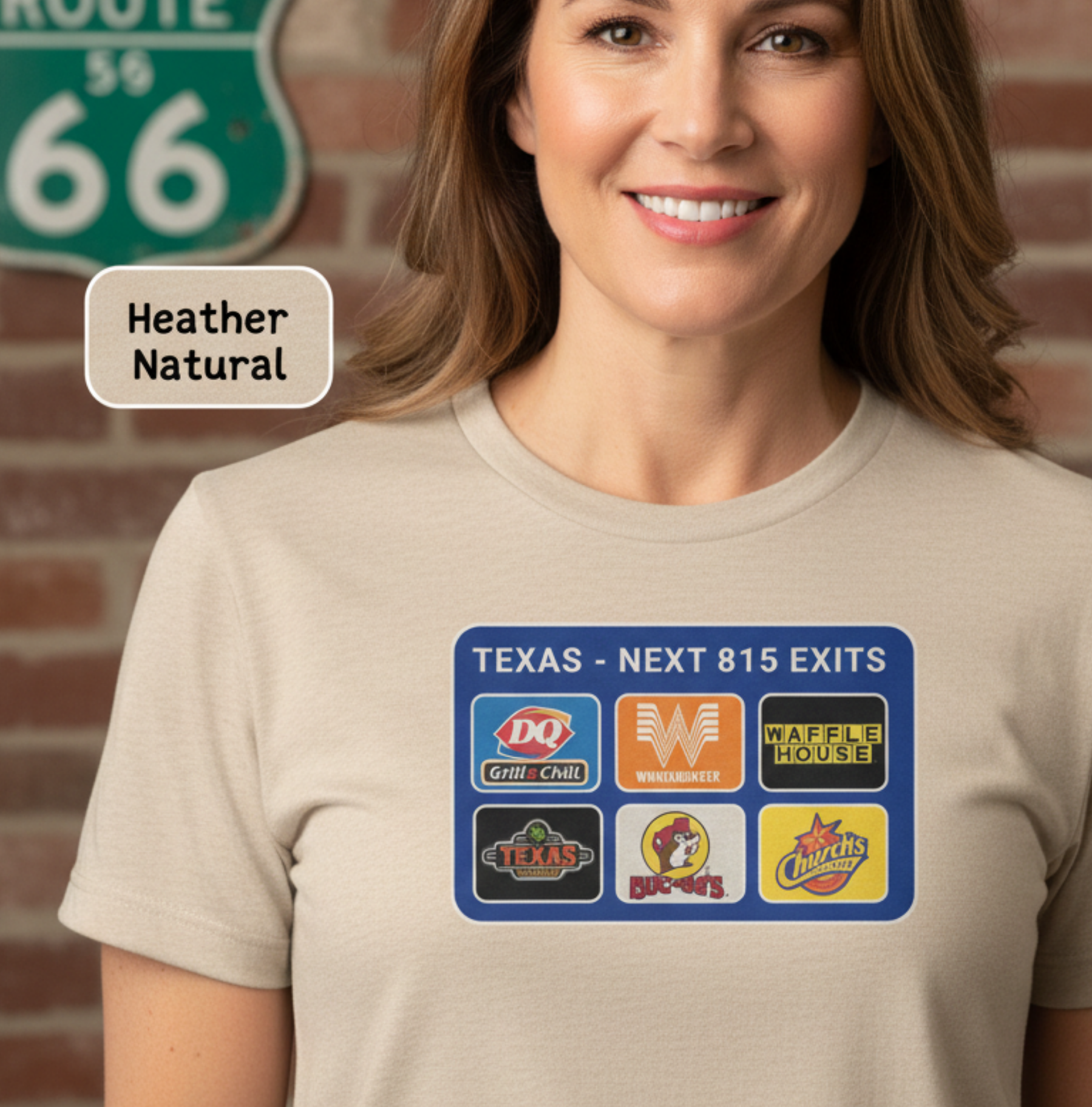 Woman wearing a beige t-shirt with various logos on it, standing in front of a brick wall with a Route 66 sign.