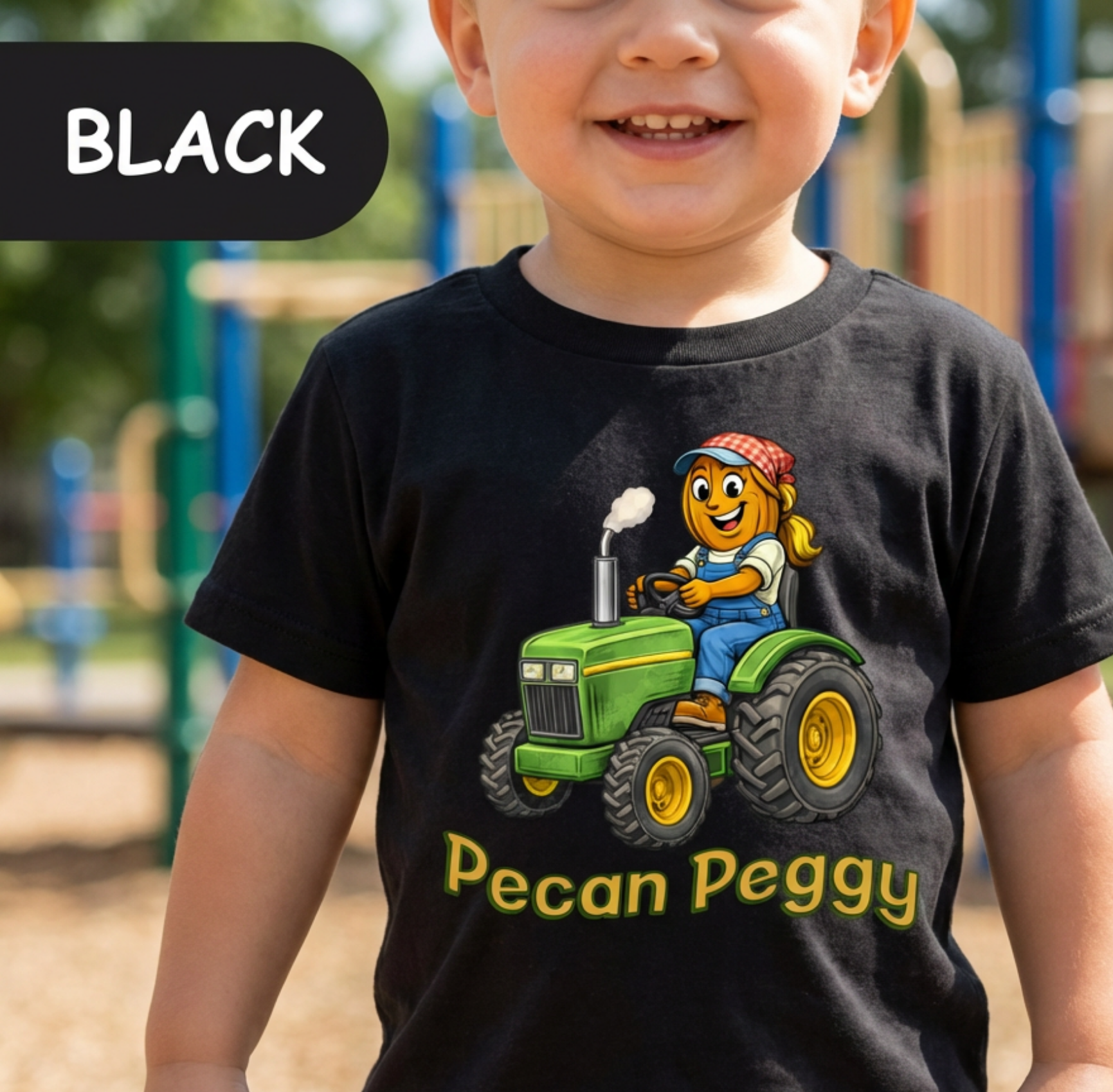 Child wearing a black t-shirt with a cartoon character on a green tractor and 'Pecan Peggy' text, outdoors.