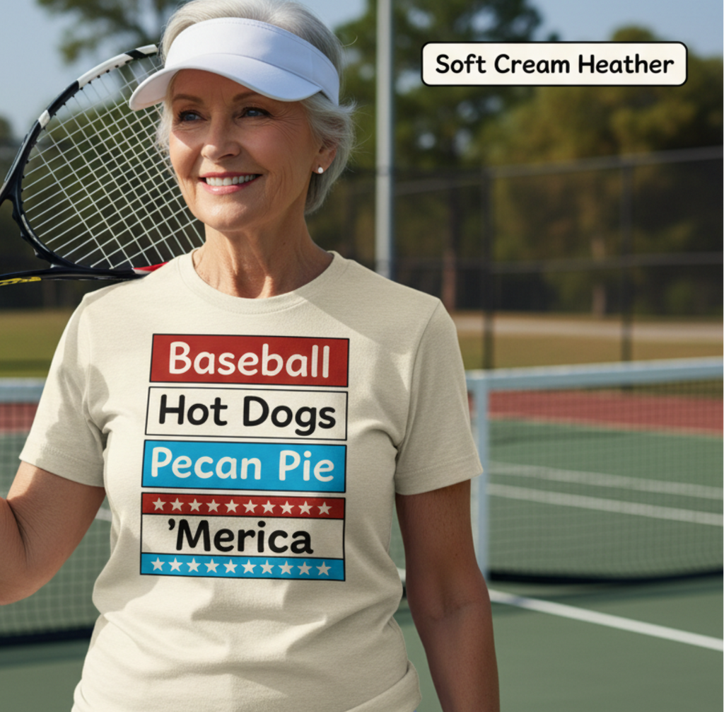 Woman on a tennis court wearing a t-shirt with patriotic text, holding a tennis racket.