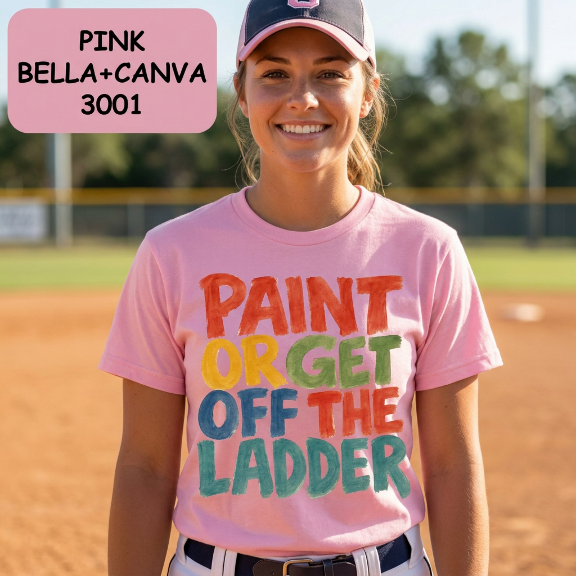 Softball girl wearing a pink t-shirt with colorful text on a baseball field, with 'Pink Bella+Canvas 3001' text overlay.