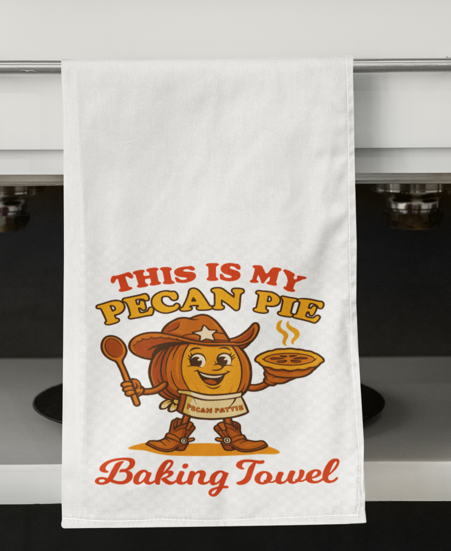 Illustration of Pecan Pattie, a smiling cowgirl pecan character in boots and hat, holding a steaming pie with the phrase “This Is My Pecan Pie Baking Towel” in bold retro lettering.