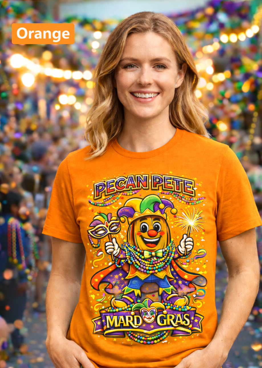 Smiling model wearing a colorful Mardi Gras Pecan Pete graphic T-shirt, featuring a festive jester pecan character with beads, mask, sparkler, and parade confetti, photographed against a lively Mardi Gras celebration background.