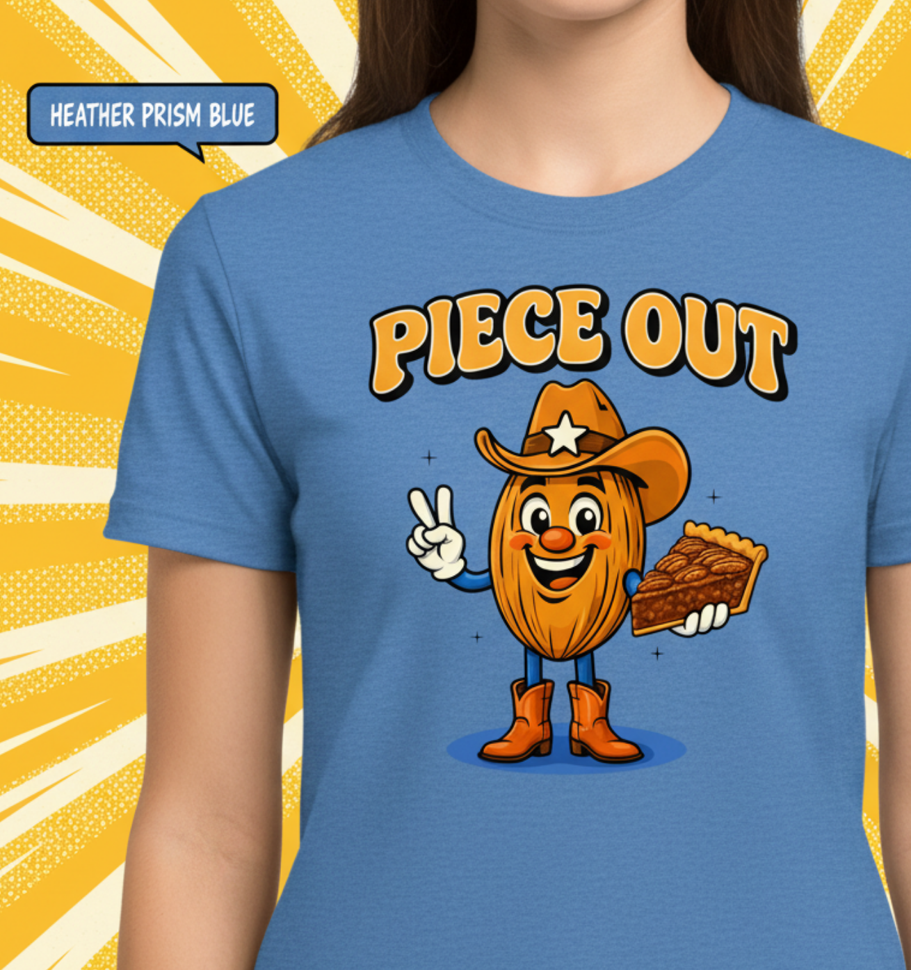 A woman wearing a heather prism blue t-shirt with a cartoon graphic of an avocado character in a cowboy hat holding a slice of pie, with the text 'PIECE OUT' above it. The background is a yellow sunburst pattern.