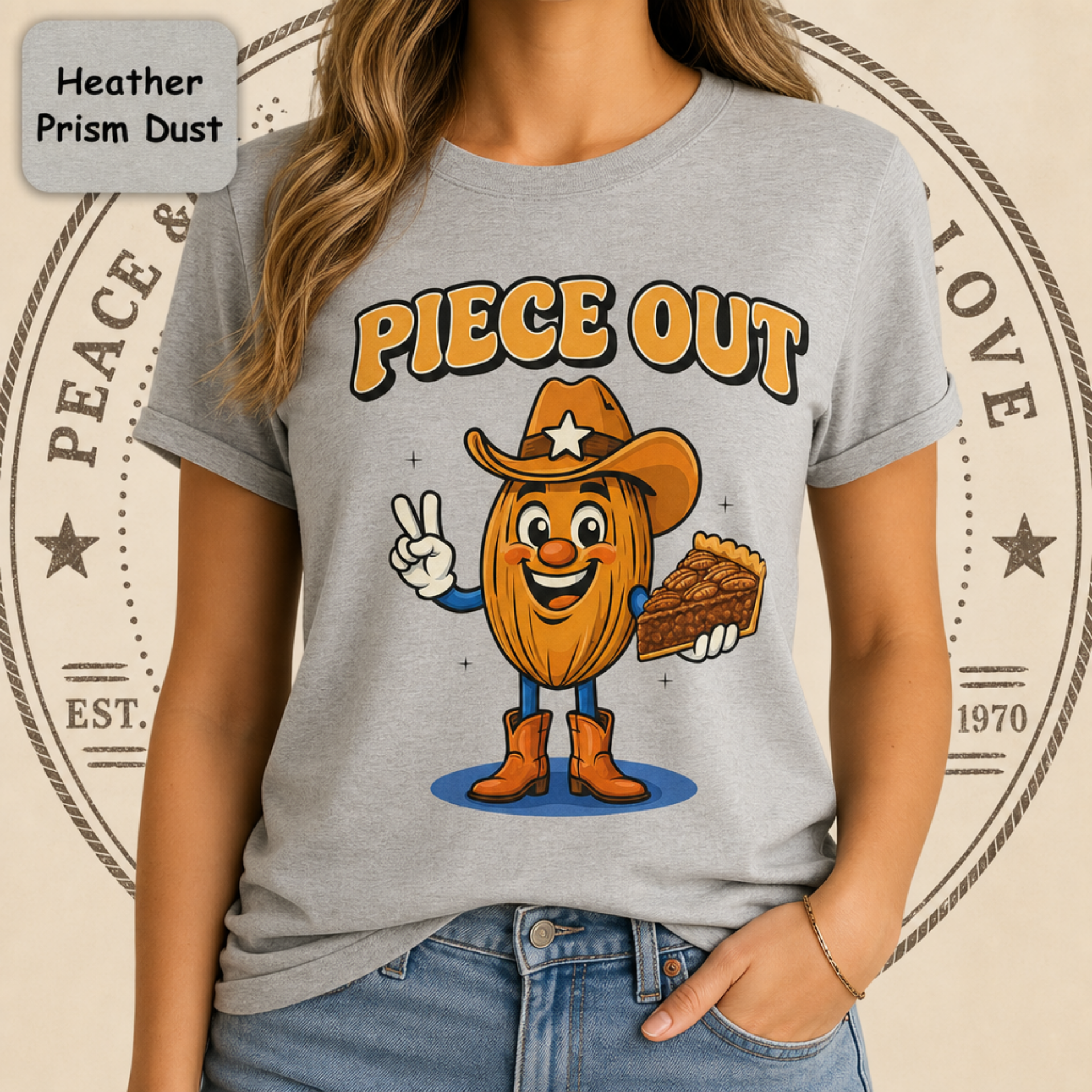 A woman wearing a heather gray t-shirt with a cartoon graphic of an almond character wearing a cowboy hat and boots, holding a slice of pie next to the text 'PIECE OUT'.