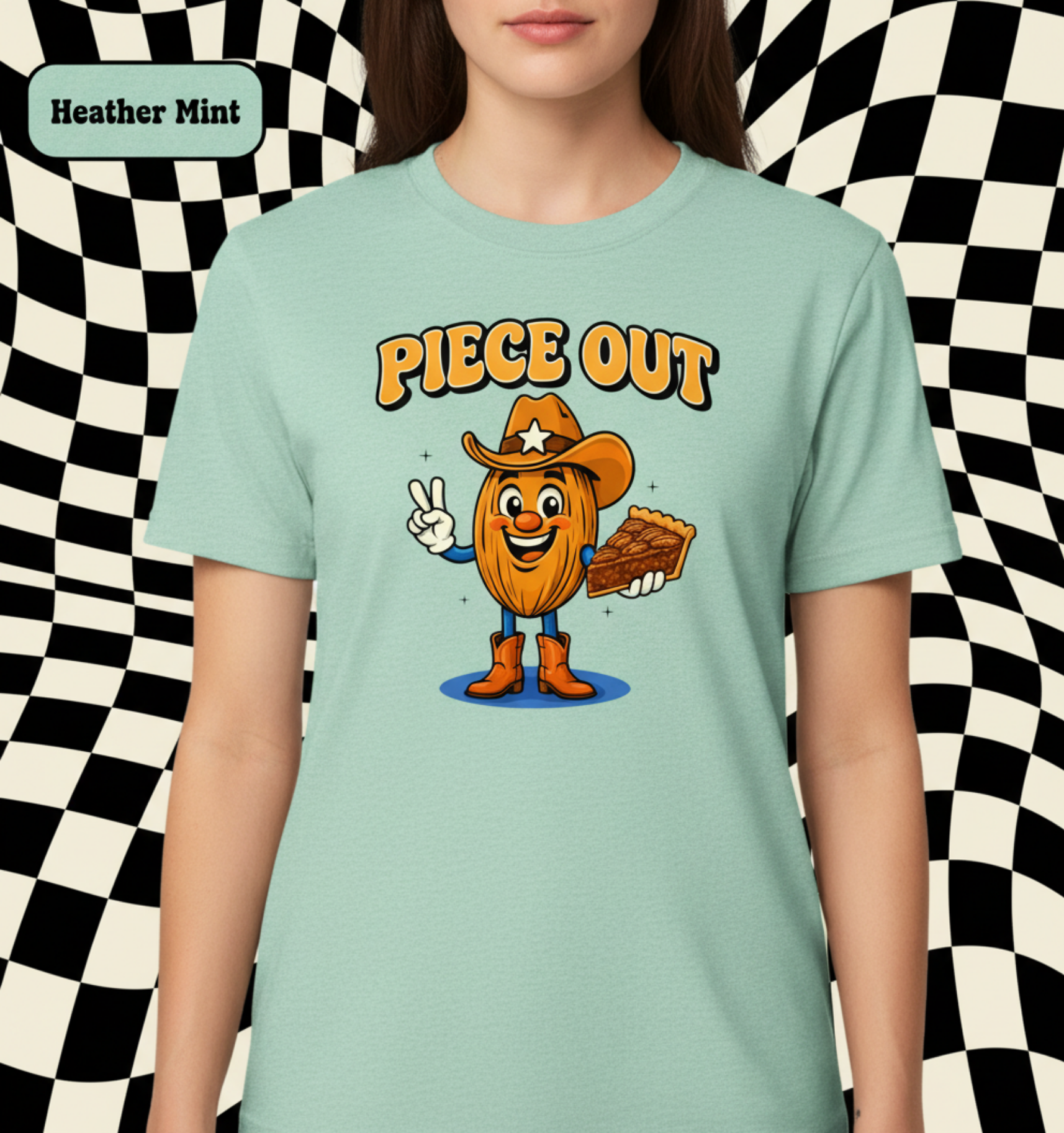 A person wearing a heather mint graphic T-shirt against a dark starry space background. The shirt has a cartoon nut character wearing a cowboy hat and boots with the text 'PIECE OUT' above it.