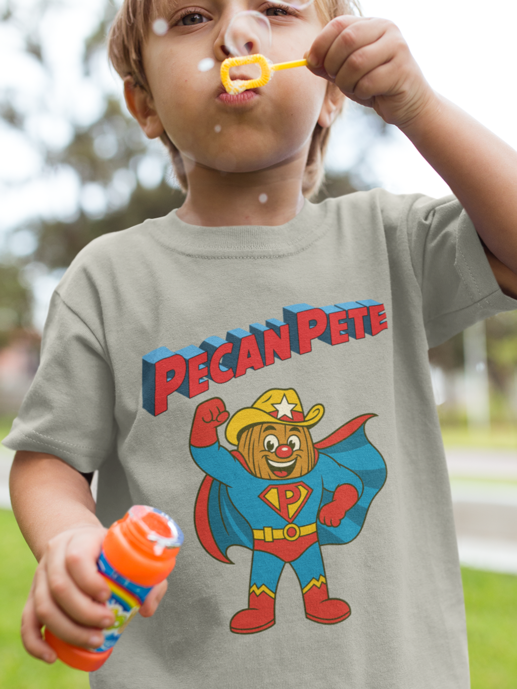 “Cartoon superhero Pecan Pete in blue and red costume with cape and cowboy hat on NuttyMerch youth tee – retro comic style superhero design.”