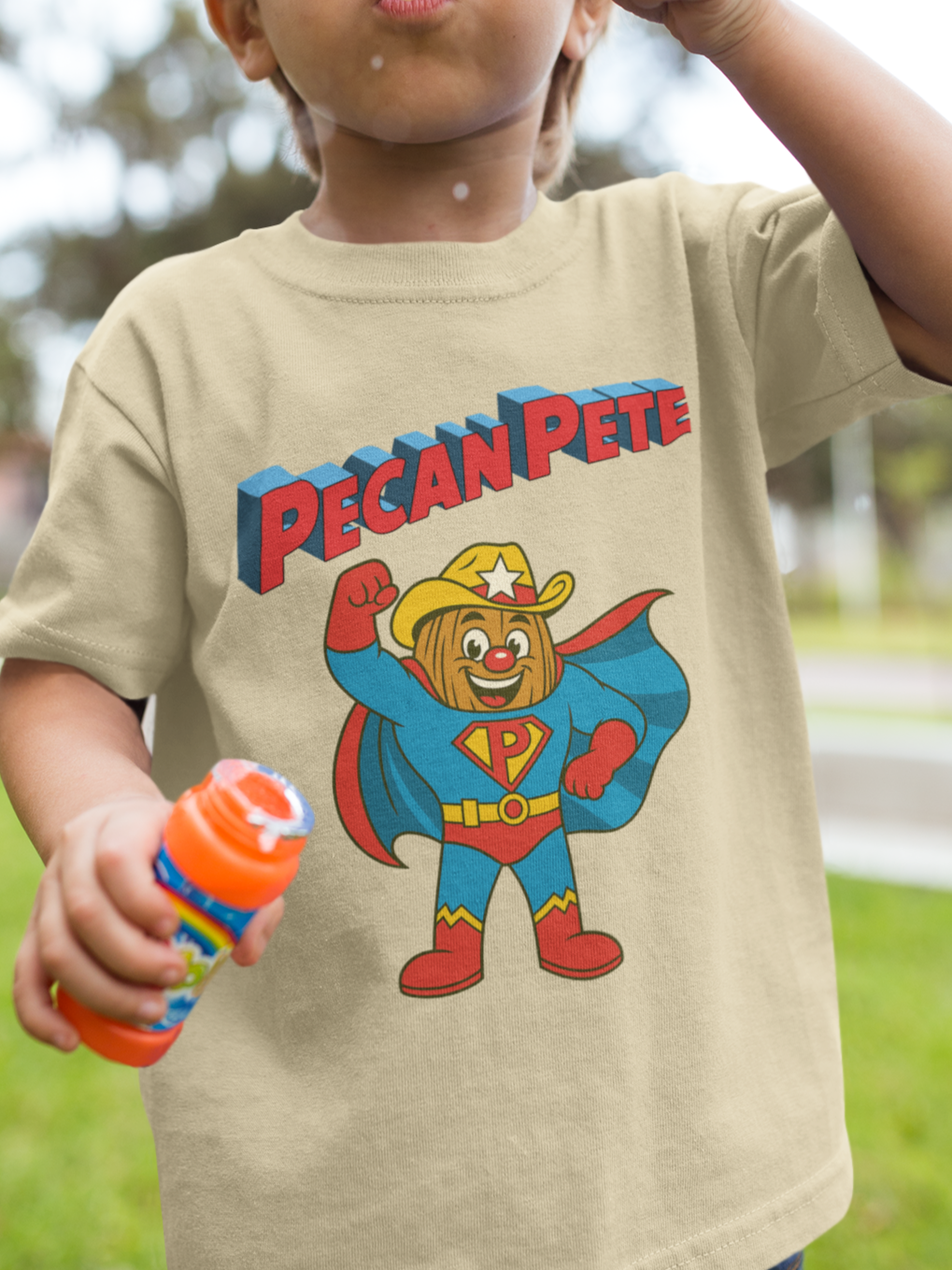 “Cartoon superhero Pecan Pete in blue and red costume with cape and cowboy hat on NuttyMerch youth tee – retro comic style superhero design.”