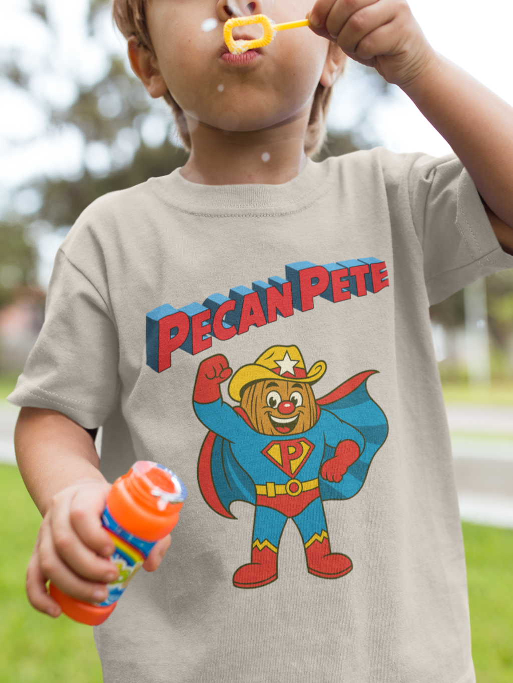 “Cartoon superhero Pecan Pete in blue and red costume with cape and cowboy hat on NuttyMerch youth tee – retro comic style superhero design.”