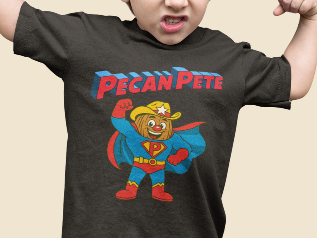 “Cartoon superhero Pecan Pete in blue and red costume with cape and cowboy hat on NuttyMerch youth tee – retro comic style superhero design.”