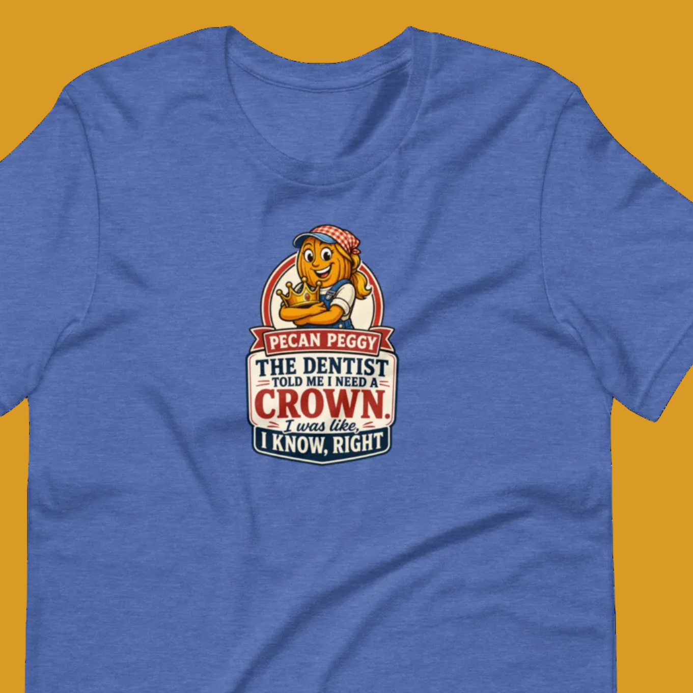 A heather blue short-sleeve t-shirt with a cartoon graphic on the chest. The graphic features a lion wearing glasses and a bandana, with text that reads 'I CAN SEE PIGGY THE DENTIST AND I WANT A CROWN.