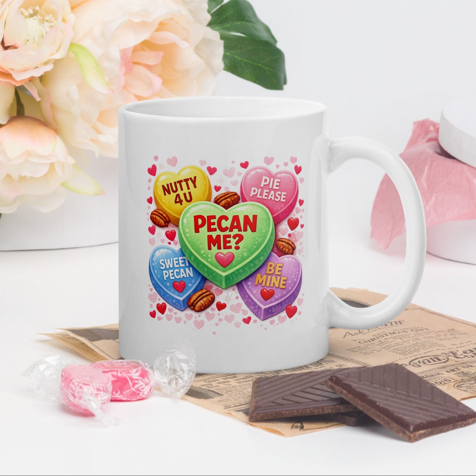 White 11oz ceramic coffee mug with pastel Valentine candy hearts design and text “PECAN ME?” plus “Nutty 4 U” and “Pie Please” on a pink Valentine background.